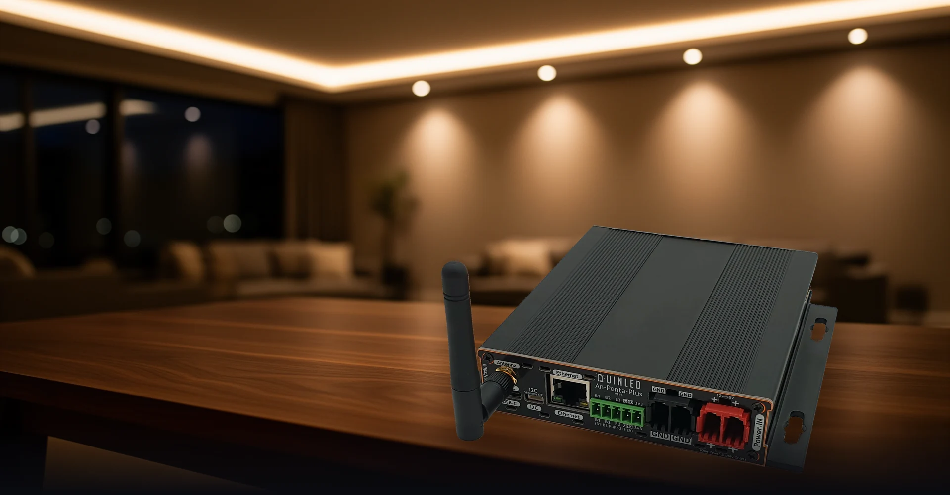 QuinLED An-Penta-Plus analog LED controller with copper PCB edge and color-coded terminals on a warm-lit dark stage